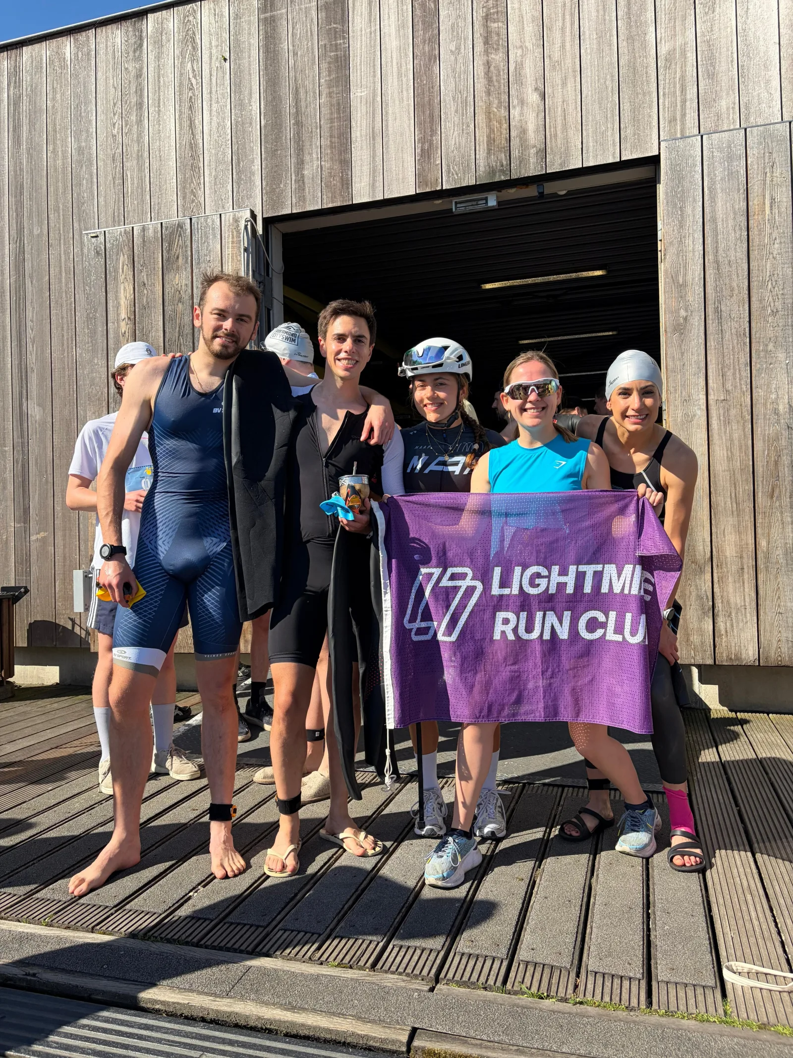 Lightmile triathletes holding a club flag after a session